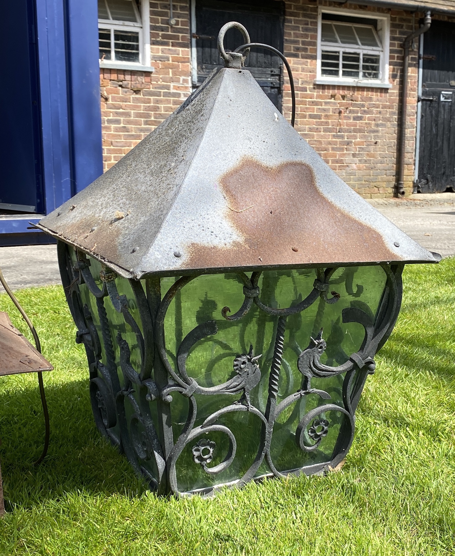 A wrought iron square shaped hanging lantern, height 67cm x 50cm, width; another, smaller lantern and a 1950’s Murano blown amber glass and wire work lantern (3)